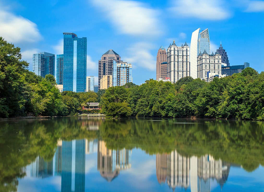 Contact - Aerial View of Atlanta, Georgia Displaying Skyscrapers and a Park With a Lake Reflecting the Tall Buildings on a Sunny Day