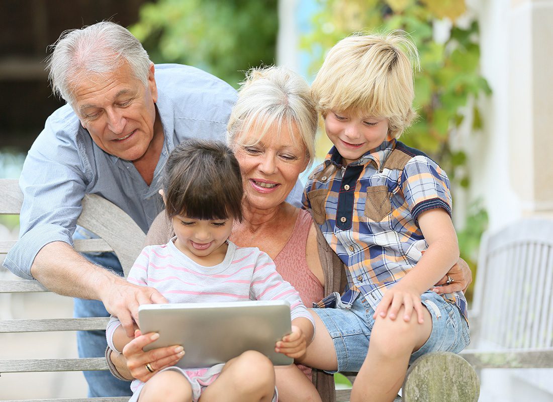 Service Center - Grandparents and Their Two Young Grandchildren Sit Together Using a Tablet