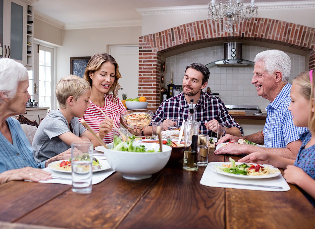 Personal Insurance - Happy Family Sitting Down Together at a Dining Room Table Sharing a Meal